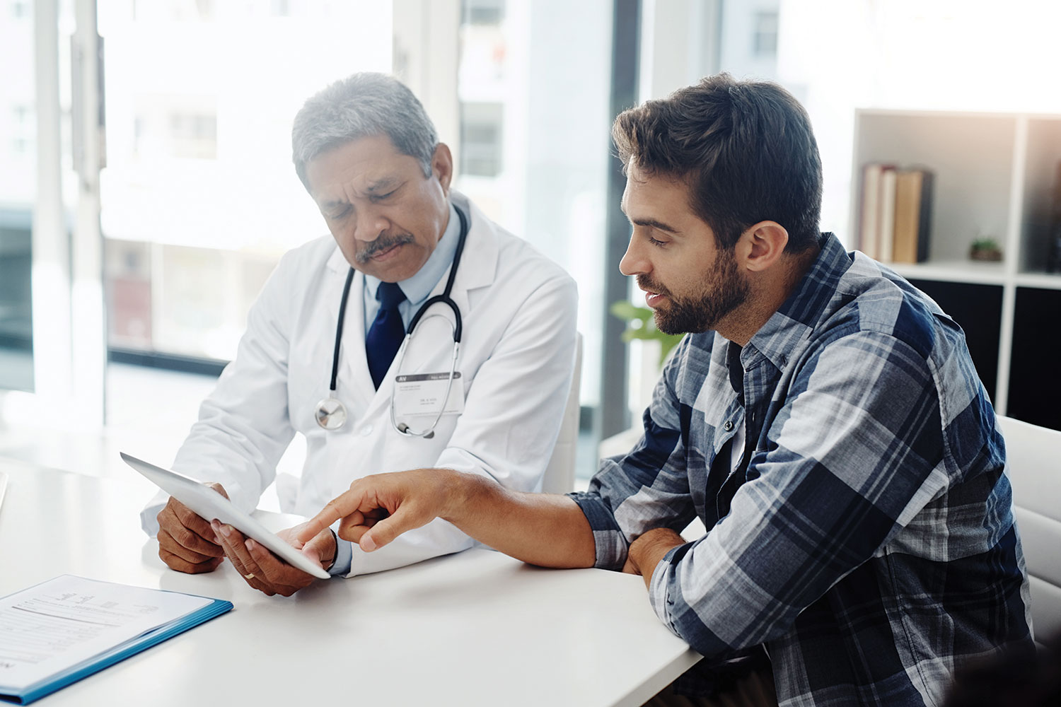 photo of older male doctor with younger male patient looking at test results