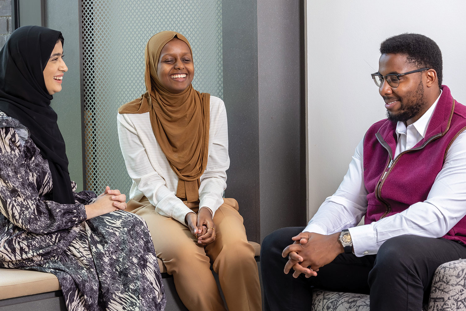 photo of three Impact graduates sitting chatting and smiling at one of the local government graduate programme’s residential learning events.