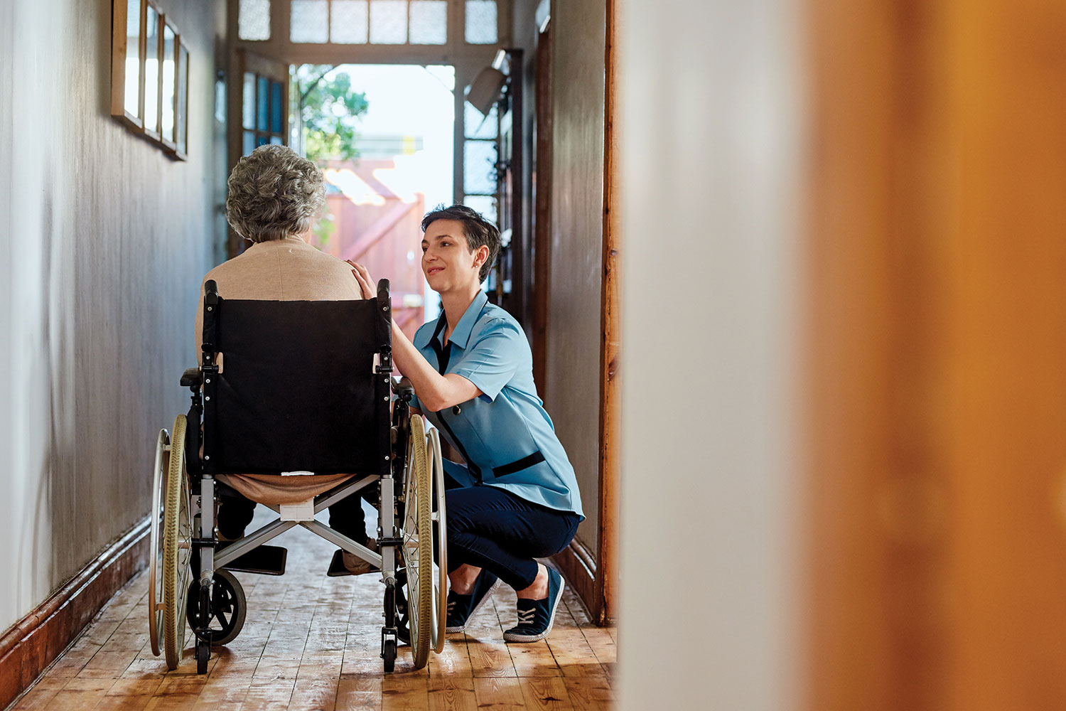 a carer talking to an elderly woman sitting on a wheelchair