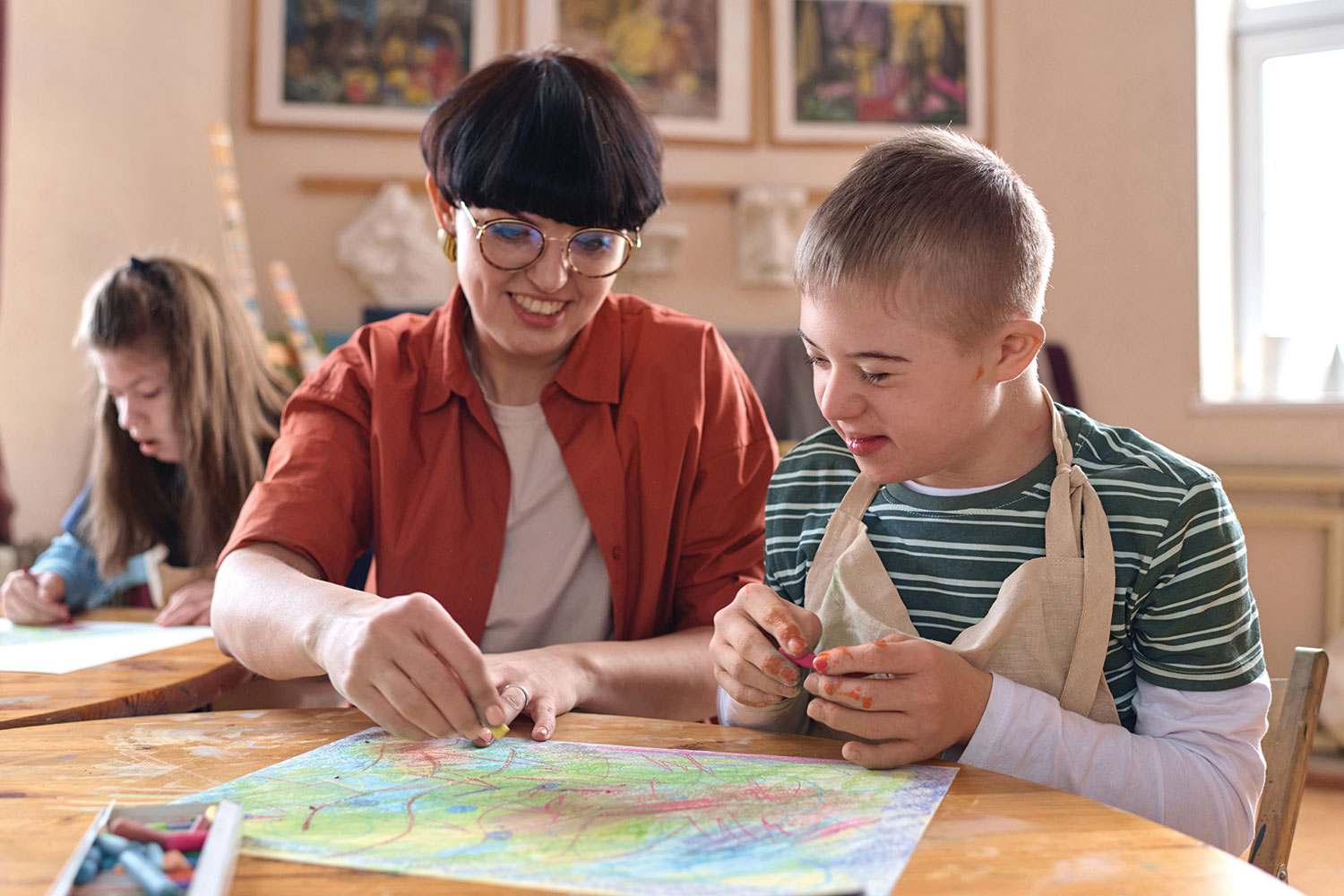 Woman carer colouring with crayons with young client with learning disabilities.