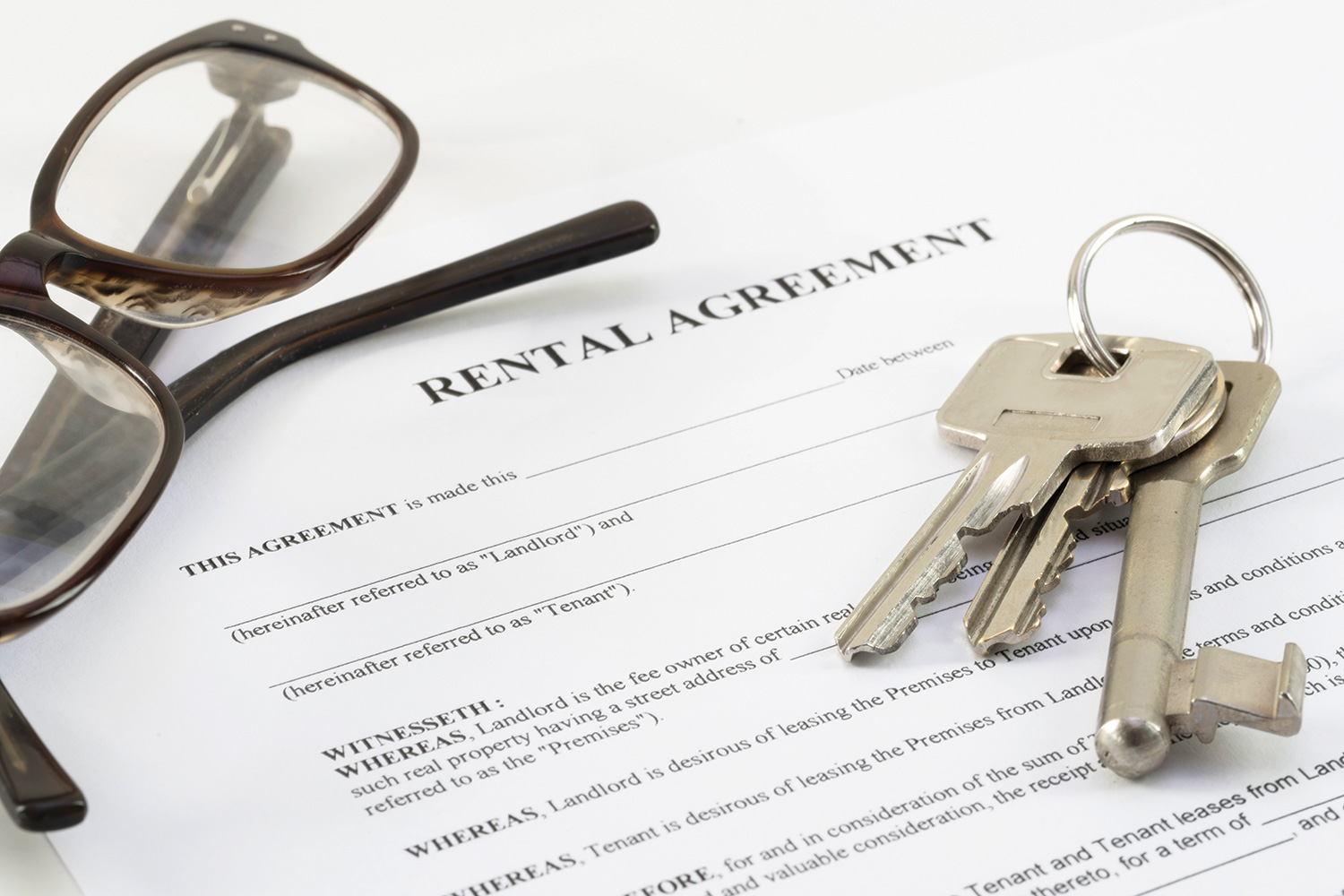 reading glasses and bunch of keys lying on printed out rental agreement.