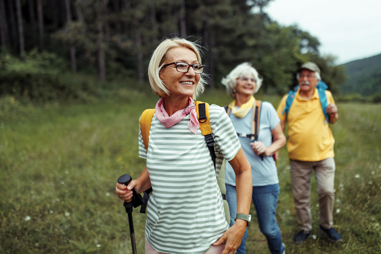 two middle aged women and a man out hiking on a hillside