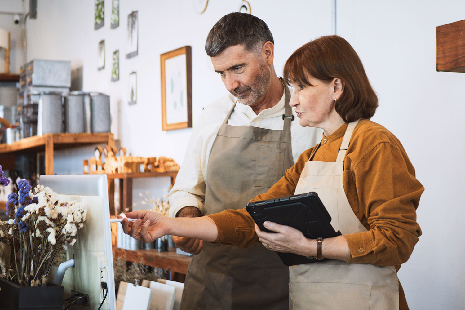 photos of staff in aprons in small retail shop (flowers, coffee, lamps in background