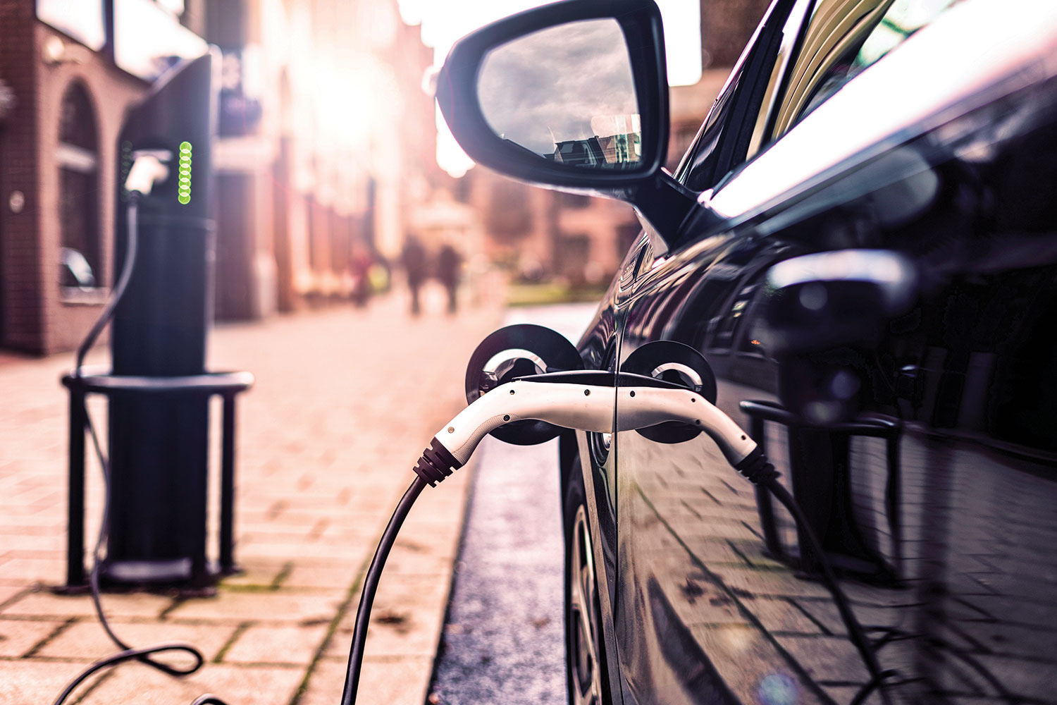 Close-up of side of car plugged into on-street electric vehicle charger.